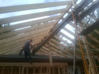 Rafters going up over a new addition with a worker on the wall in Sarahsville