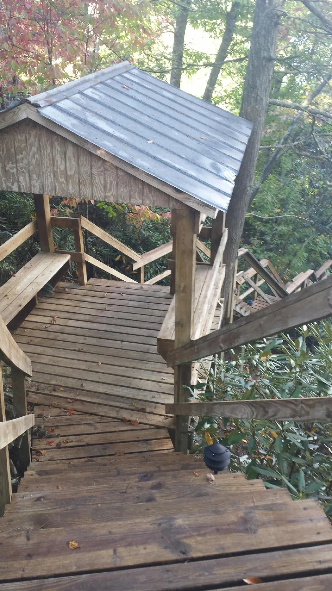 Metal roofed shelter over wooden steps on a wooded walkway — Skylight Repair & Installation work by our crew in Sarahsville