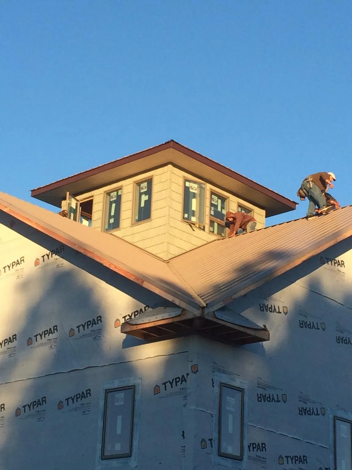 Roofers working around a rooftop cupola on a new metal roof at sunset — Roof Waterproofing in Sarahsville by Roofing Brothers